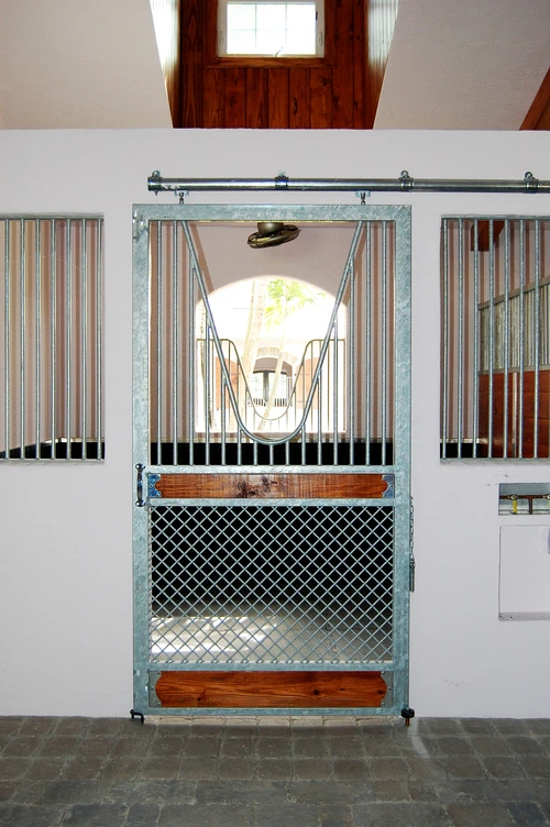 Turquoise sliding barn door with vertical bars and diamond mesh grille