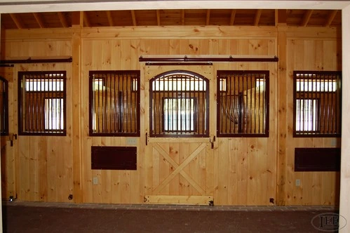 Light wood five-bay stall front with arched window cutouts and dark metal bars