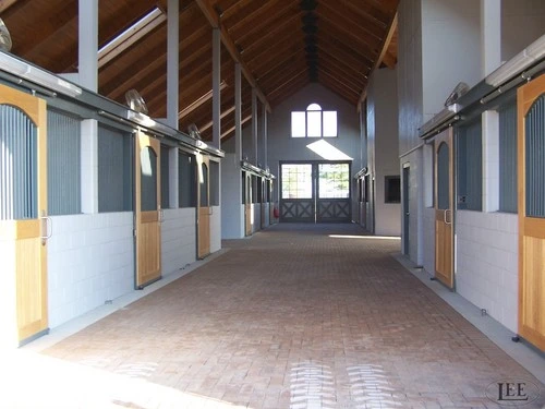 Bright barn aisle with white walls and light wood sliding stall doors