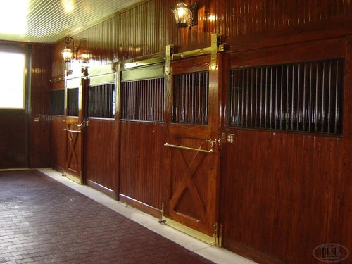 Polished mahogany sliding stall doors with brass hardware in upscale barn