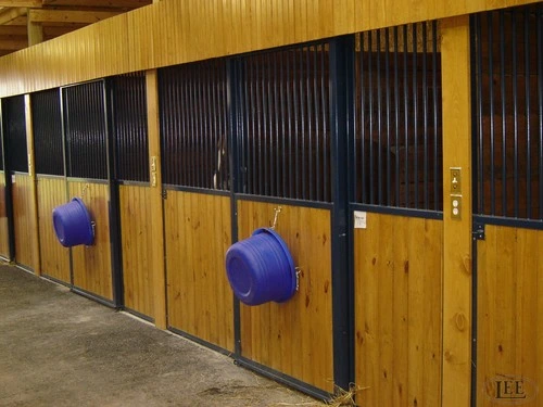 Golden pine stalls with black bar doors and purple feed buckets mounted outside