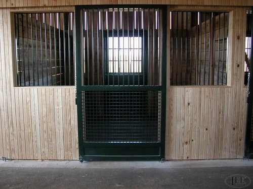 Whitewashed wood stalls with dark green wire mesh sliding doors