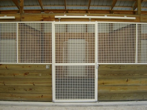 A natural pine sliding door with wire mesh panels in white barn setting