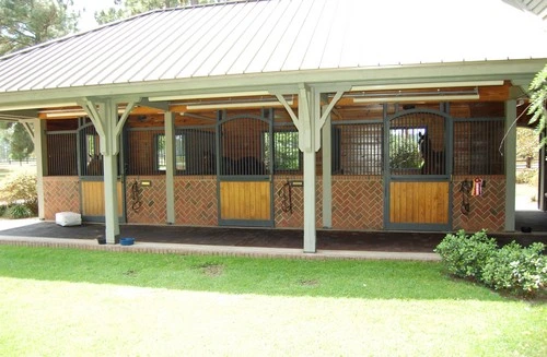 Covered outdoor pavilion with three horse stalls featuring lattice work and half doors