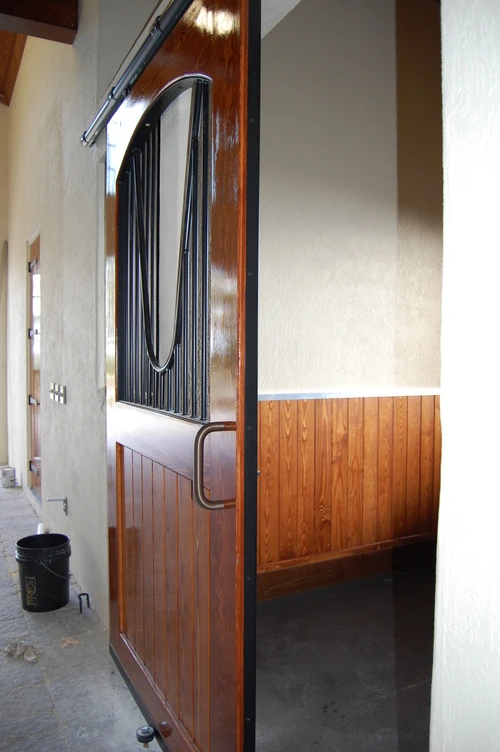 Barn aisle with white upper walls and natural wood lower stall sections
