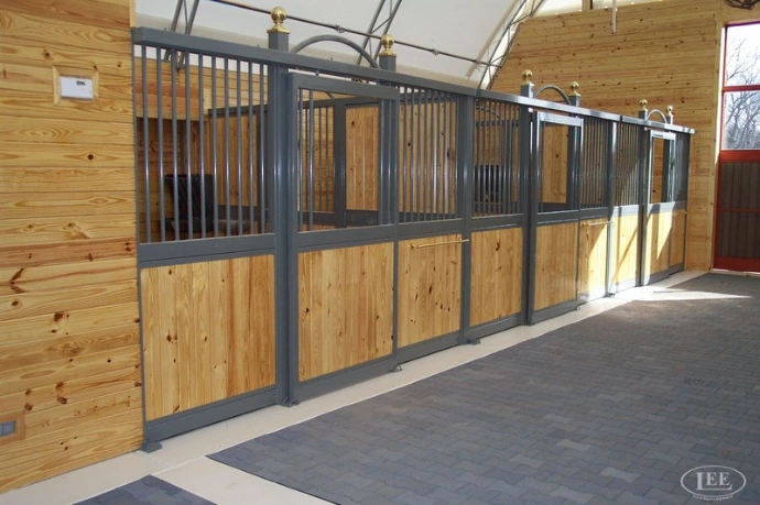 Long barn corridor with gray-framed stalls and natural wood panels