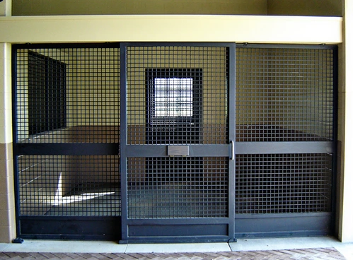 Black metal stall fronts with grid mesh lower panels in modern barn with tiled floor