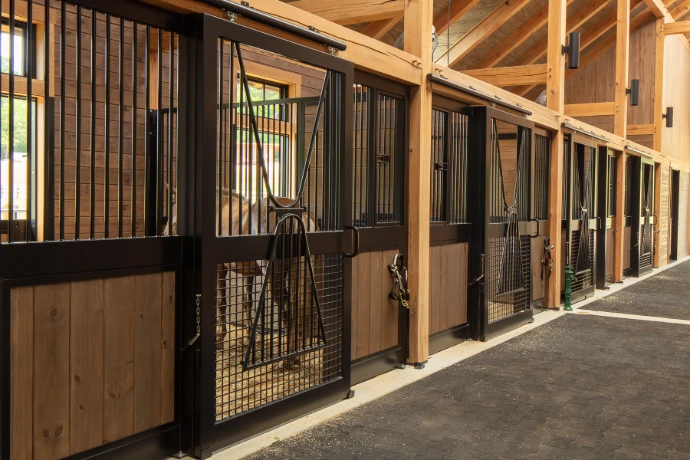 Black metal stall fronts with natural pine lower panels and wire mesh doors in timber-frame barn