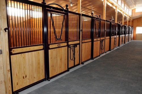 Long perspective of black metal stall fronts with rich mahogany lower panels in luxury barn