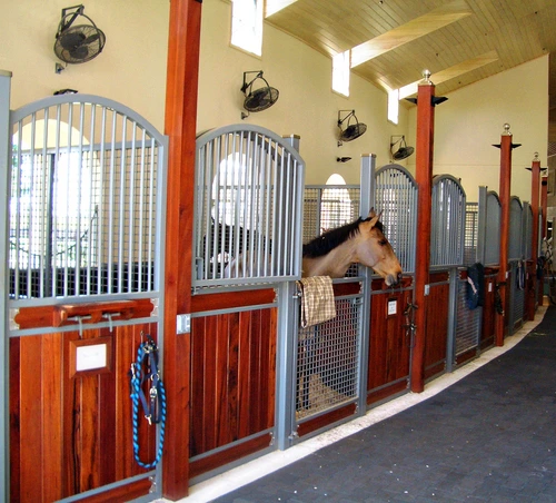 White stucco building with natural wood and black metal arched stall fronts in Mediterranean style