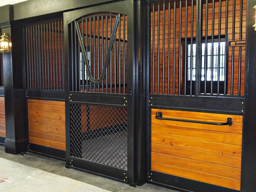 Black metal stall fronts with rich mahogany lower panels and wire mesh sections in luxury barn