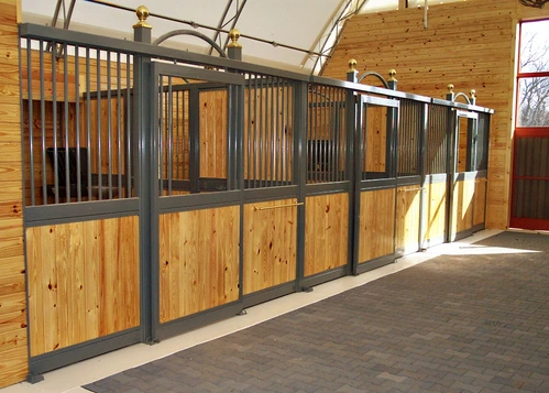 Long barn aisle with sage green stall fronts, natural pine lower panels and black vertical bar upper grills