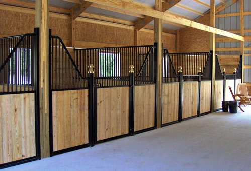 Black metal stall fronts with natural wood lower panels and vertical bar upper grills in bright modern barn