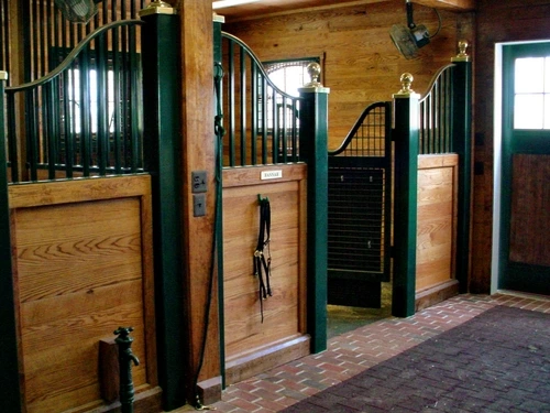 Forest green stall front with natural pine lower panel and vertical bar upper grill in corner with louvered vent