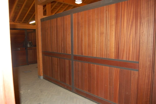 Rich mahogany vertical plank stall front with black horizontal bar grill section in bright interior