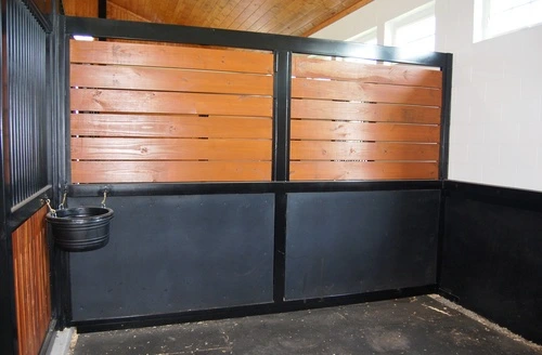 Dark stall front with horizontal wood upper panels and solid black lower sections with rubber mat flooring