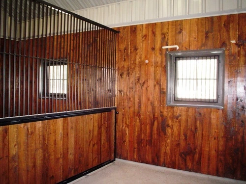 Natural wood vertical plank stall with corrugated metal upper section and barred window