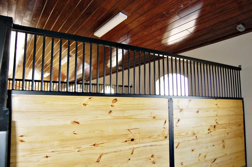 Light pine stall front with black metal vertical bar upper grill in bright interior with wood plank ceiling