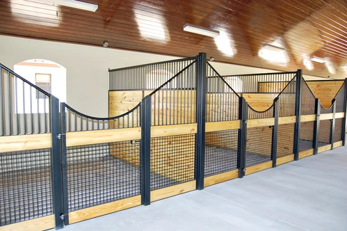 Blue metal curved stall fronts with wire mesh panels and decorative rope swags in white barn interior