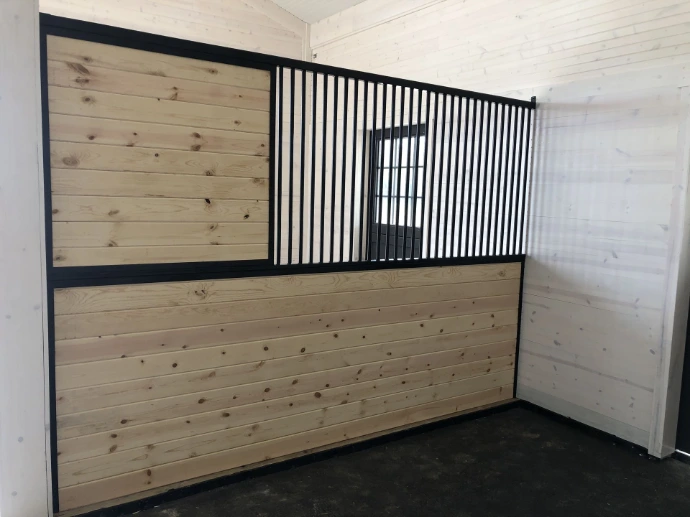 Natural pine stall interior with black vertical bar upper grill and tongue-and-groove wood lower walls