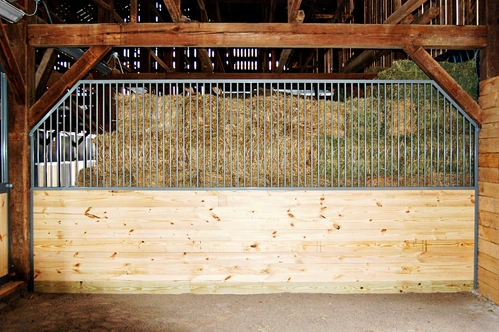 Timber-frame stall under wooden arch with vertical bar metal upper grill and light wood lower section