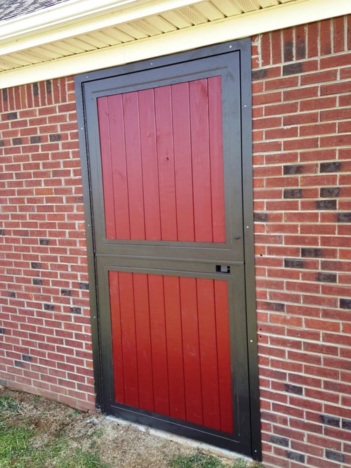 Red vertical plank door with gray metal frame on red brick exterior wall