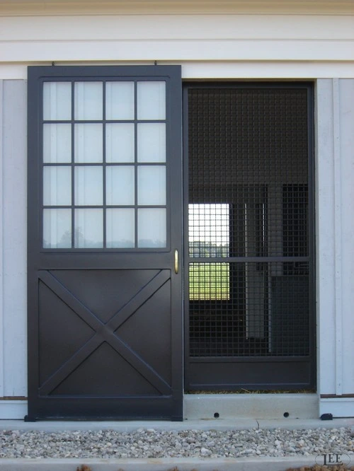 Dark gray metal door with multi-pane window and mesh panel on white wall