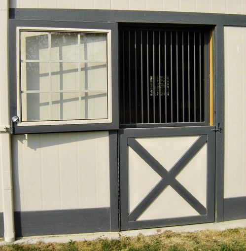 Cream colored Dutch door with black vertical bar upper grill and X-pattern lower panel