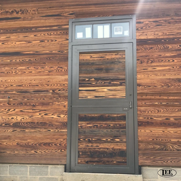 Gray metal Dutch door with horizontal slat vent panel on natural wood plank siding