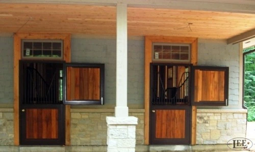 Interior covered barn aisle with mahogany Dutch doors featuring horizontal slat grills and transom windows