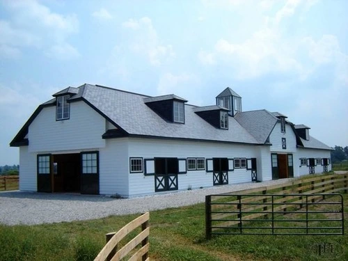 White barn complex with black X-pattern Dutch doors and black trim under gambrel roof
