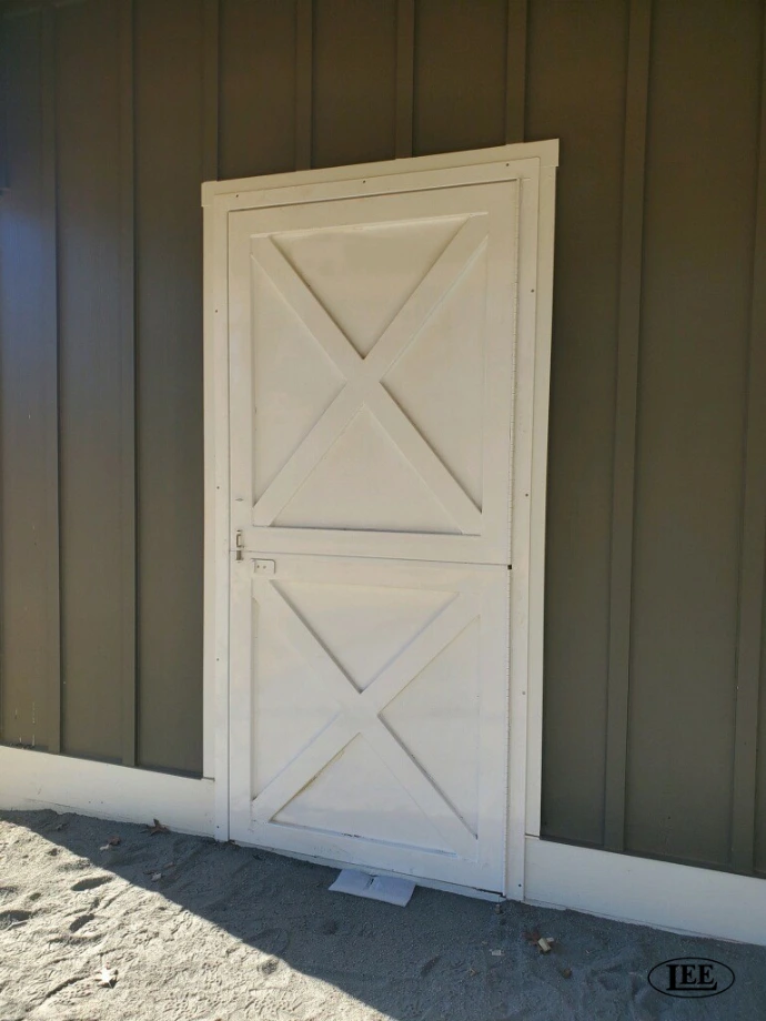 White painted Dutch door with diagonal panel design centered between gray-green trim walls