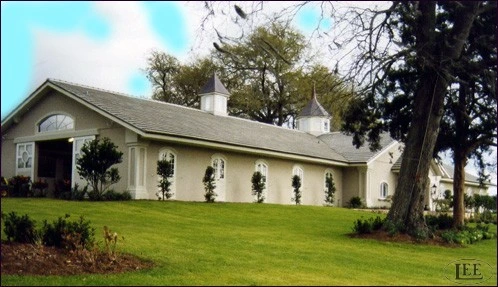White painted barn with arched openings and black wall-mounted carriage lanterns