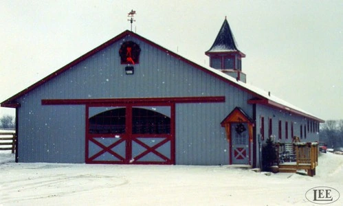 Gray metal barn with burgundy trim, red X-pattern sliding doors and cupola