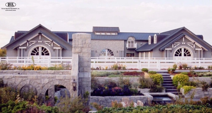 Stone building facade with symmetrical arched openings and tiered landscaping