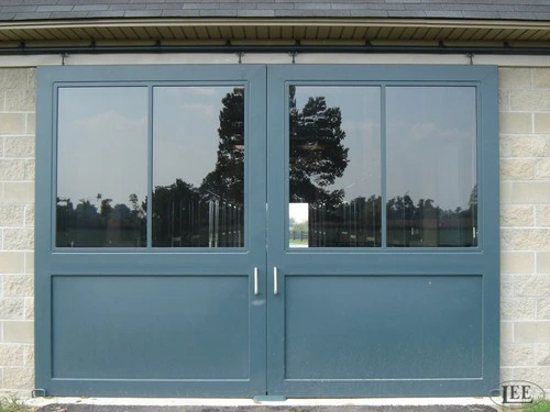 Blue-gray double doors with upper glass window sections on cream stucco wall