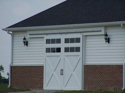 White barn with carriage-style doors featuring multi-pane windows and X-brace pattern
