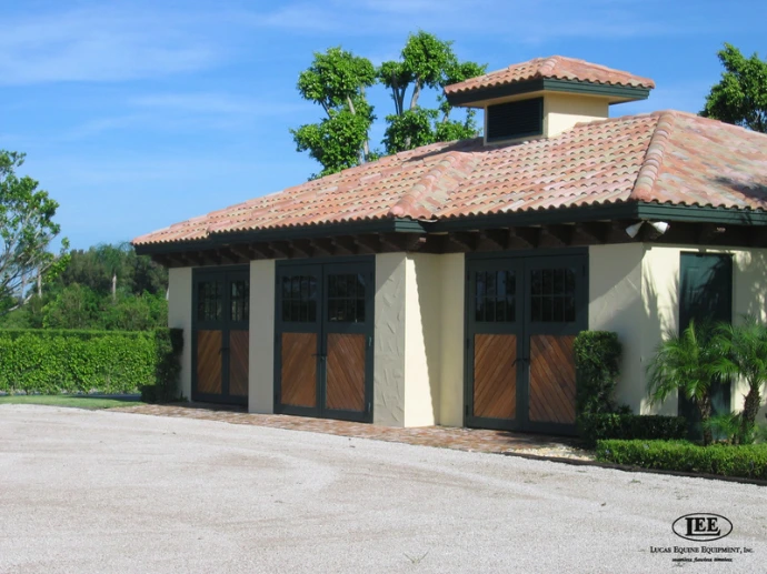 Mediterranean stucco barn with arched wood sliding doors under terracotta tile roof