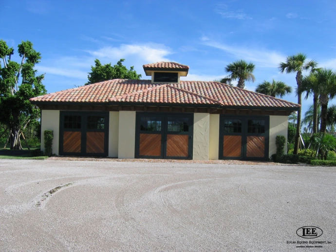 Stucco building exterior with three arched wood sliding doors and palm trees