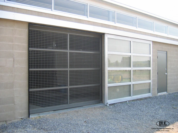 Modern barn aisle with gray metal framed mesh panel doors and overhead lighting