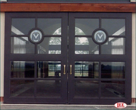 Black metal double doors with circular monogram details and multi-pane glass sections