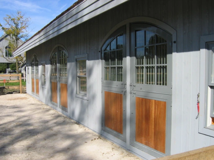 White barn corridor with arched openings and natural wood lower stall sections