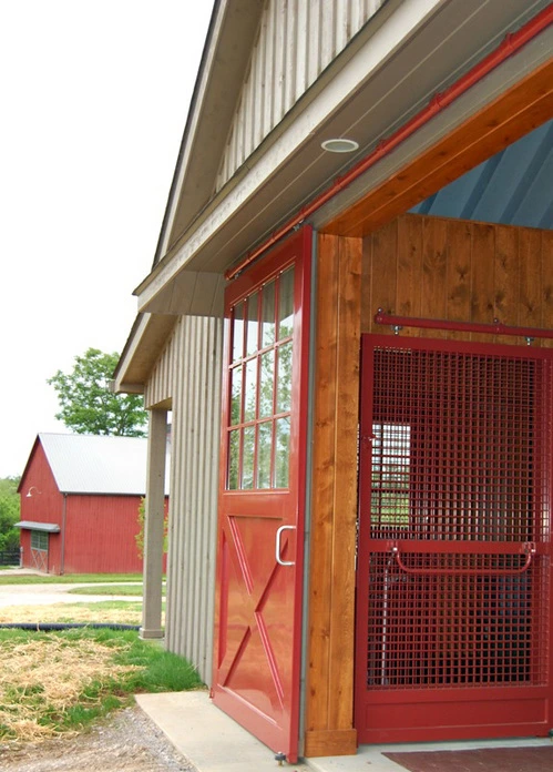 Natural wood barn interior corner with red metal mesh stall panels