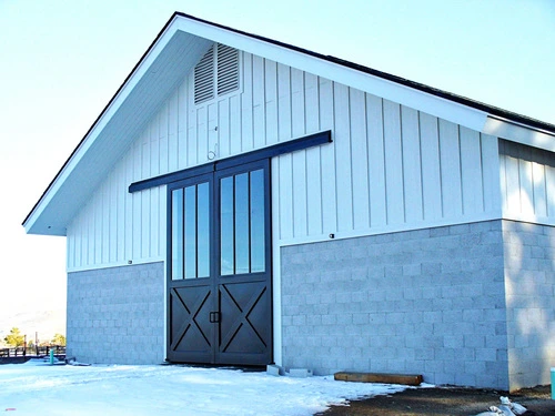 Blue barn exterior with black X-pattern sliding door and vertical siding