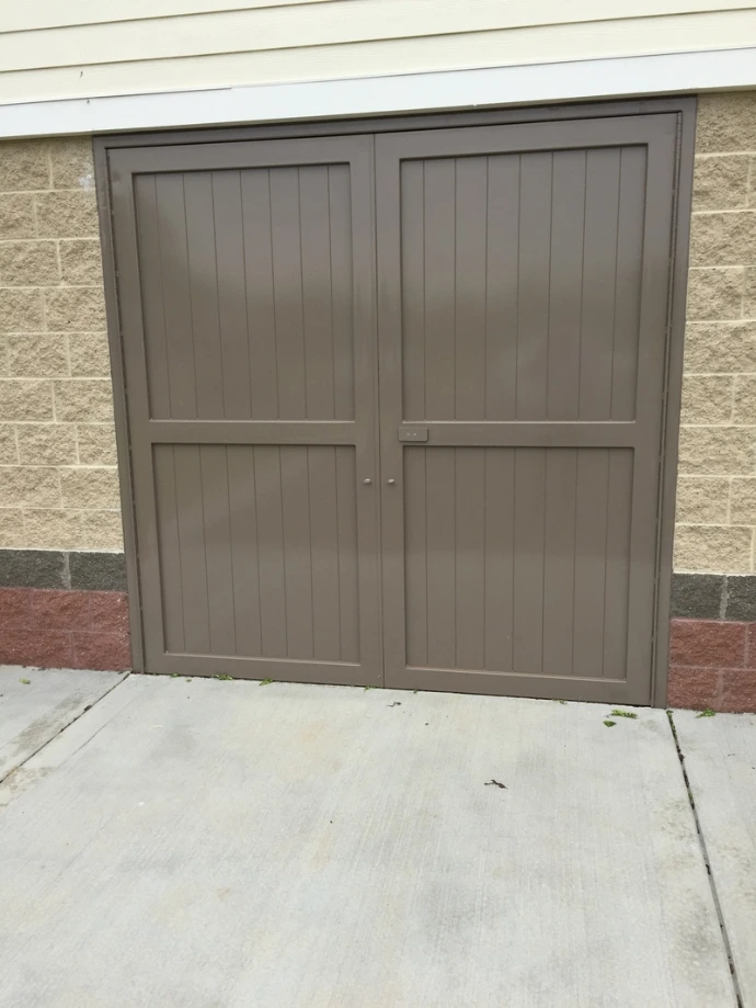 Taupe painted double doors with horizontal panel design on stucco exterior