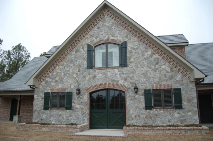 Stone facade barn with green shutters and arched mahogany door openings