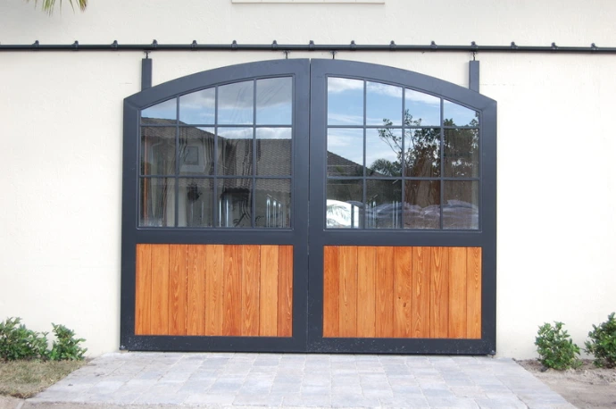 Dark gray metal framed arched doors with upper glass and lower wood panels on white stucco
