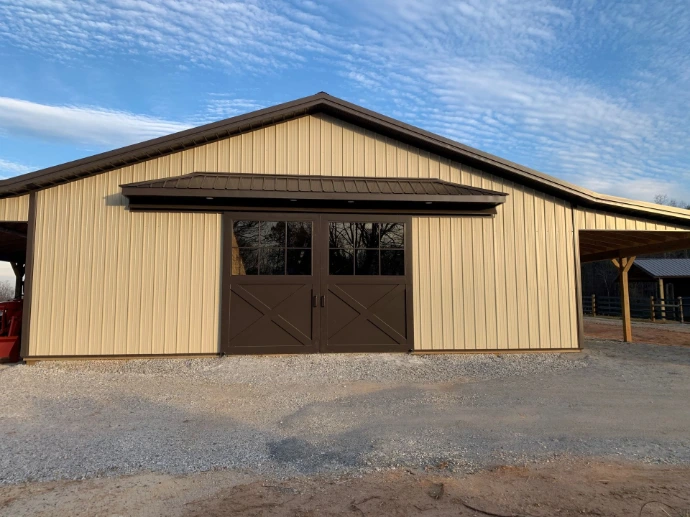 Tan metal barn with natural wood sliding doors featuring upper window panels