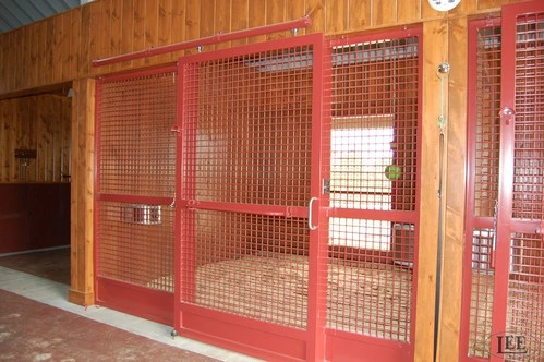 Red metal stall doors with wire mesh panels in natural wood timber-frame barn