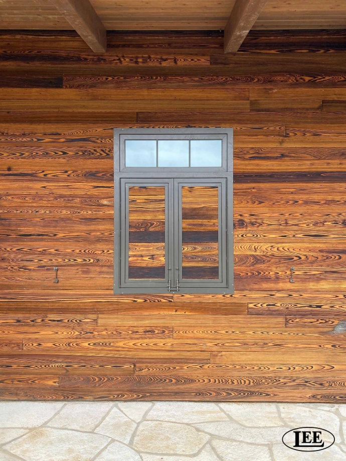 Gray metal Dutch doors with glass pane inserts on reclaimed wood plank wall
